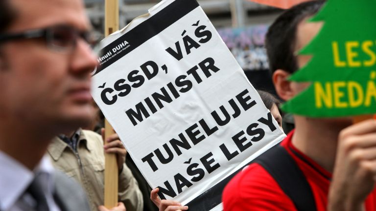 Záběr na protestní cedulku. ČSSD, váš ministr tuneluje naše lesy.
